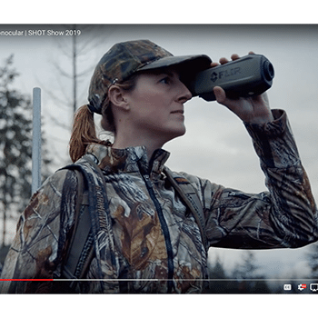 Woman in camouflage seen looking through a Teledyne FLIR Scion OTM outdoor thermal monocular.