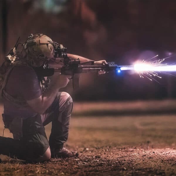 Man shown shooting a rifle at night with a US Night Vision DesignateIR-V attached.
