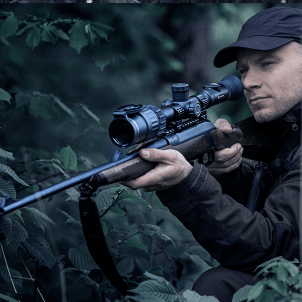 Hunter shown in the wilderness preparing to take aim through a bolt-action rifle mounted Pulsar Digex C50.